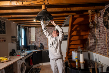 jeune homme faisant le ménage et nettoyant un luminaire dans son appartement