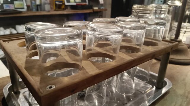 A clean arrangement of clear glasses displayed on a wooden rack in a rustic setting, perfect for beverage service or minimalist presentations,