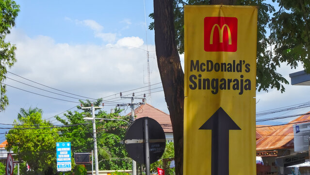 Singaraja, Bali, 05-11-2019; Roadside sign directing to a McDonald&rsquo;s restaurant in Singaraja, Bali, surrounded by tropical greenery and local roadside scenery.