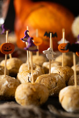 Halloween table with pumpkin cookies, festive symbols and cute decorations. Pumpkins, ghost, bat and witch hat in trendy orange, black and purple autumn colors.