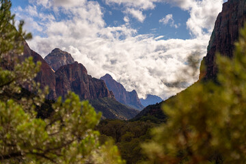 Majestic mountains under a cloudy sky, framed by trees.