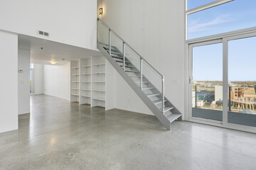 Large, empty apartment with a glass staircase leading to the second floor