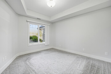Large, empty room with a window and a light fixture