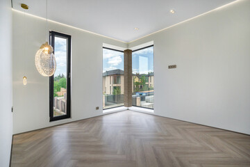 Bright room featuring large corner windows that offer a view of outdoor greenery. Light wood flooring enhances the spacious feel of the area. Perfect for designing a cozy living space.