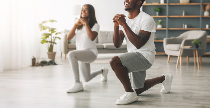 Home Fitness. Full body length of motivated black couple doing forward lunges in living room. Handsome guy and his girlfriend working out together, training leg muscles during coronavirus quarantine