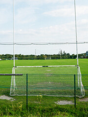 Fototapeta premium Tall goal post for Irish sport on a small training ground with green field of a small club. Camogie, hurling and rugby training ground.