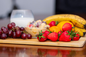 Fresh Fruit Salad with Milk, Grapes, Strawberries, Bananas, and Oranges on Wooden Board