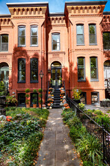 Fototapeta premium Leaf-strewn path leading to a vintage-style townhouse door. classic East Coast architecture during peak fall season.