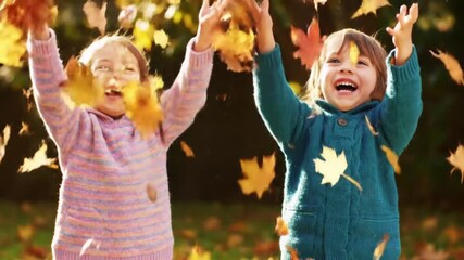 Joyful Slow Motion Video of Two Happy Children Playing and Throwing Colorful Autumn Leaves in a Sunlit Backyard