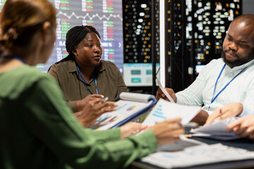 Marketing team evaluating sales and profit within infographics data, coworkers sharing insight in a...