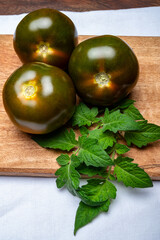 Fresh ripe sweet reddish brown and green kumato tomatoes on board