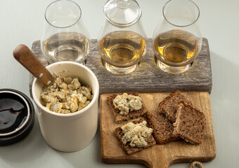 Matured strong british blue cheese stilton keeping in ceramic bowl under wax layer, cheese and whiskey pairing