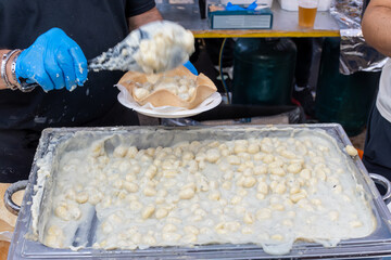 Cooking of Italian potato gnocchi with gorgonzola creamy blue cheese with in crispbread plate on local festival in Gorzonzola city, Lombardy, Italy