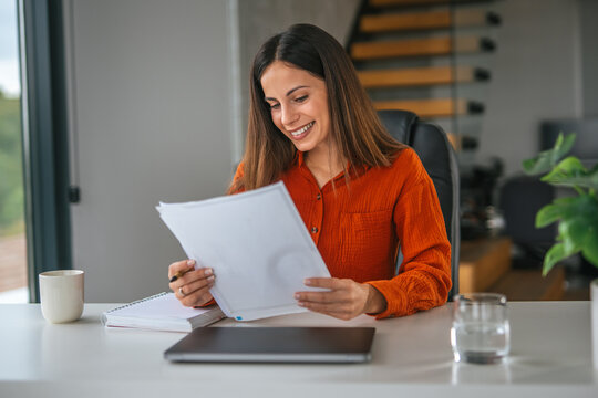 Woman reading documents smiling working from home office