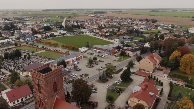 A picturesque drone flight backwards over Pępowew in Wielkopolska, revealing the historic Church of St. Jadwiga and the autumn landscape of the province.