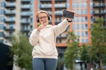 Happy woman with headphones taking urban selfie