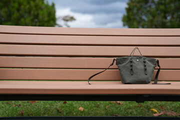 A small purse is sitting on a bench in a park