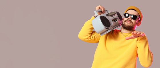 Cool male hip-hop dancer with tape-recorder on grey background with space for text