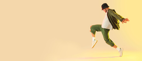 Cool young man dancing hip-hop on color background with space for text