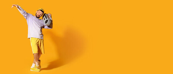 Cool male hip-hop dancer with tape-recorder on yellow background with space for text