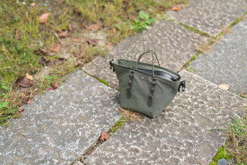 A small green purse is laying on a stone walkway