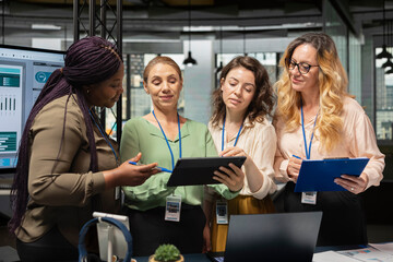 Diverse goals oriented businesswomen showcase the power of teamwork, collaborating on boardroom planning with data analytics and monthly financial reports. Corporate work environment.