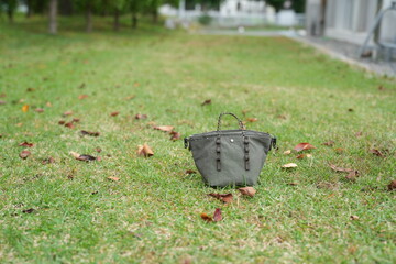 A small purse is sitting on the grass in a park