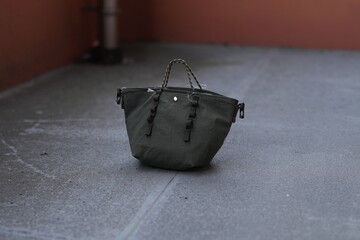 A small green purse is laying on the ground