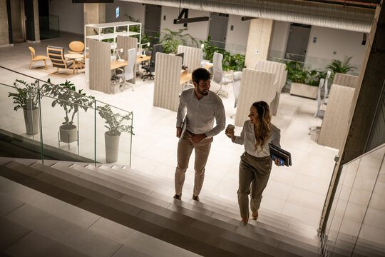 Business colleagues walking up stairs in modern office