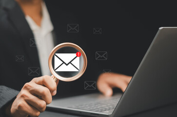 Businessman using a magnifying glass sending newsletters and engaging contacting clients or customers and networking online. Business communication and marketing networking online.