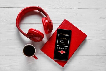 Modern mobile phone, headphones, coffee and book on white wooden background. Audiobook concept
