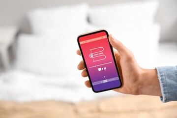 Man holding mobile phone in bedroom, closeup. Audiobook concept