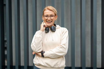 Happy mature woman with headphones smiling outdoors