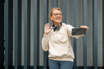 Mature woman taking selfie, waving during video call