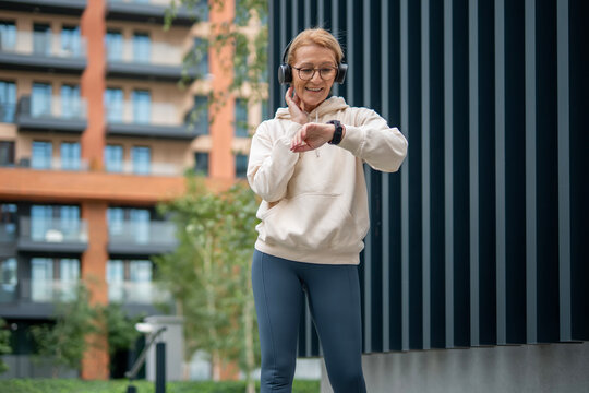 Mature woman checking pulse and smartwatch during outdoor workout - Powered by Adobe