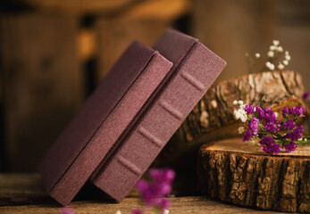 Beautifully arranged purple cloth photo books with flowers on rustic wooden logs in a cozy indoor...