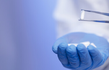 Scientist examining capsule with tweezers in laboratory setting
