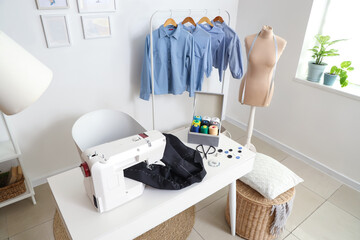 Interior of atelier with tailor's workplace, mannequin and clothes rack