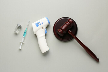Judge gavel, infrared thermometer and syringe on grey background. Concept of health care reform