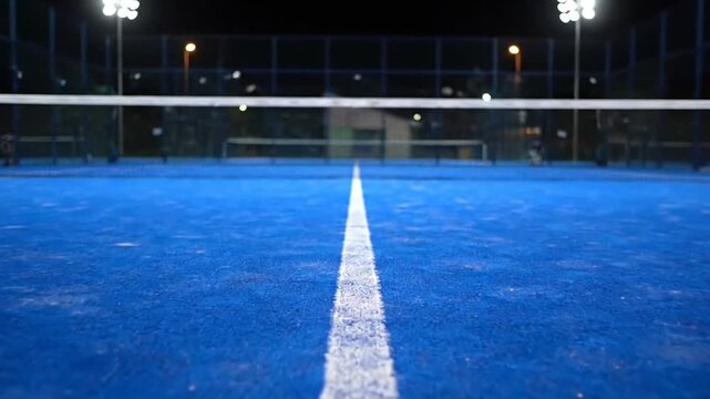 Illuminated Blue Padel Court with White Lines and Net at Night Under Bright Floodlights Sports Venue Detail View