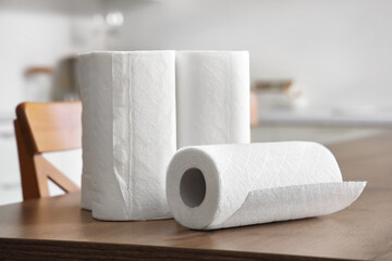 Rolls of paper towels on wooden table in kitchen, closeup