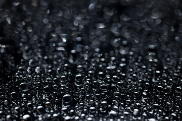 raindrops on a dark background.water drops on glass in close-up. Abstract dark background. Mockup for your logo. horizontal wallpaper or web banner.