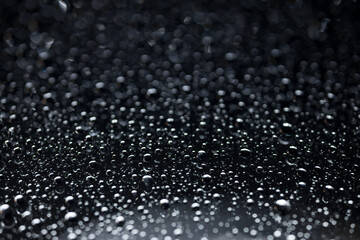 water drops on glass in close-up. abstract dark background with beautiful bokeh. Mockup for your logo. horizontal wallpaper or web banner.