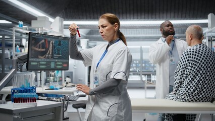 Researcher reviewing blood samples and keeps patient under observation for a clinical experiment,...