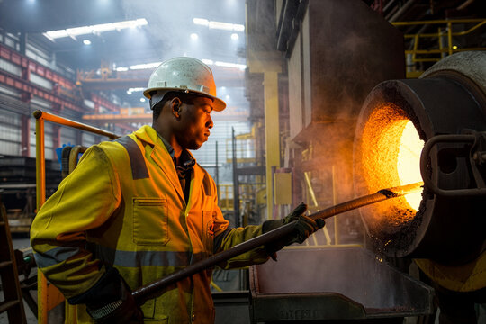 Industrial worker tending to glowing molten metal in a vibrant foundry setting