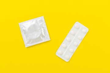 Contraceptive pills and condoms on color background, top view. birth control methods