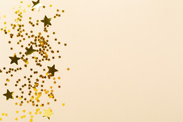 Golden star shape confetti on color background, top view