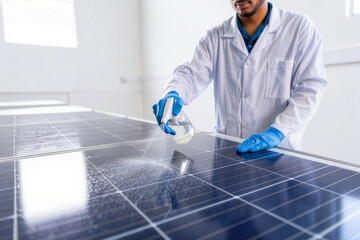 Man in lab coat cleaning solar panels with spray bottle in a bright indoor setting