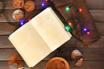 Blank recipe book with cookies and glowing Christmas lights on wooden background