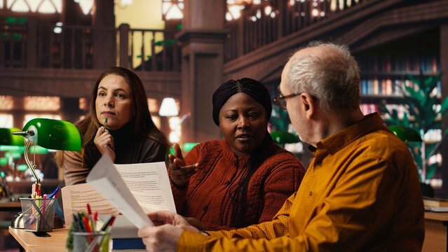 Mature team of performers rehearsing script dialogue together in a library, making drama play role preparations for character development. commitment to acting and dramaturgy.